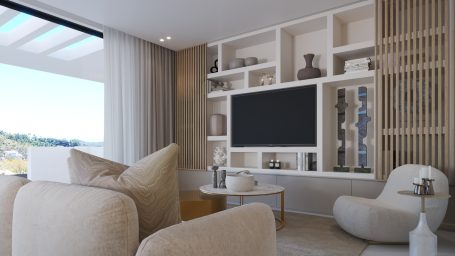 Salón moderno con muebles claros, TV montada y vistas a un paisaje exterior.