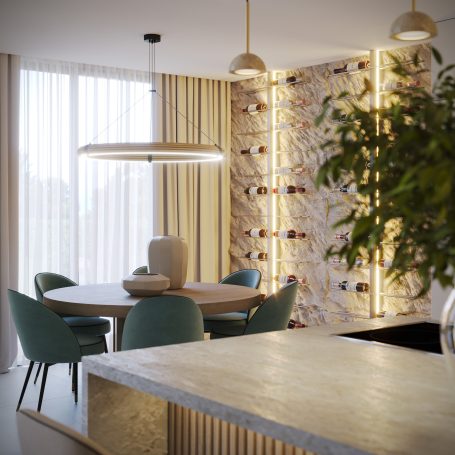 Comedor moderno con mesa circular, sillas verdes y pared iluminada de piedra.